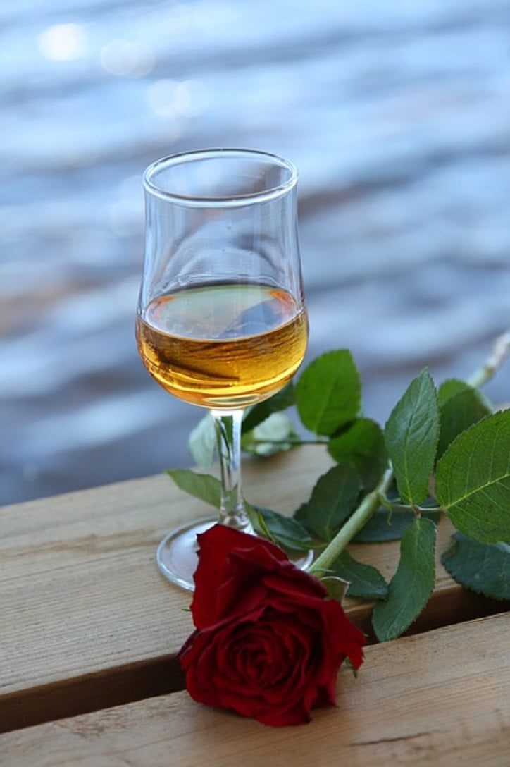 Glas mit Amaretto und einer Rose am Wasser