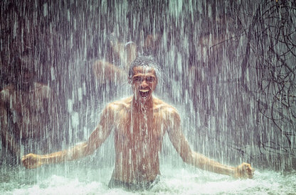 Mann unter Wasserfall