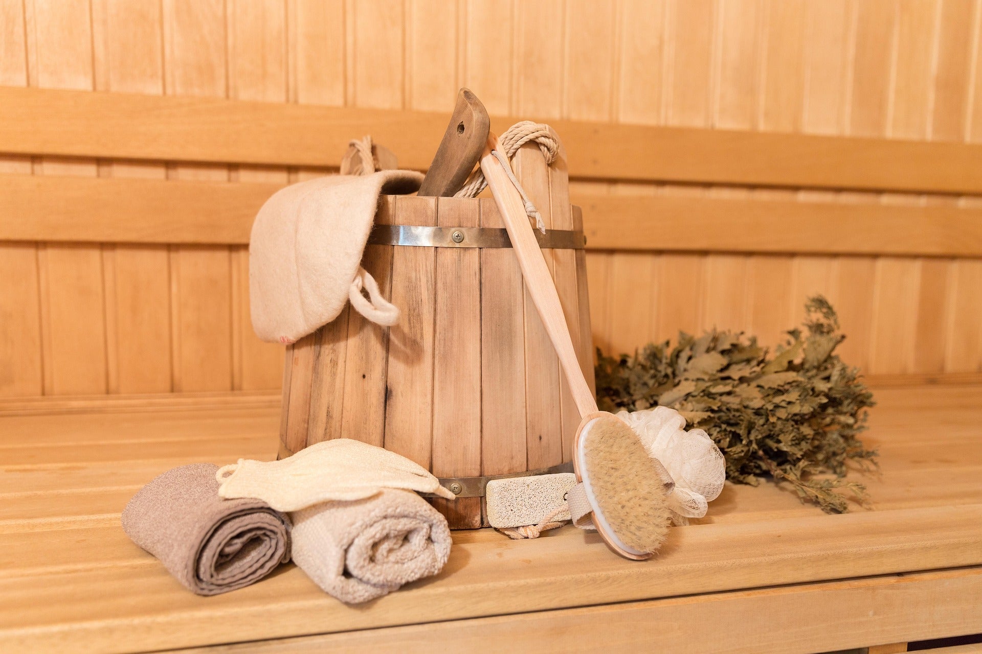 Sauna-Eimer, Kelle, Bürste, Reisig, Handtücher auf Saunabank