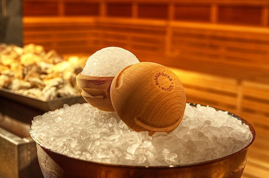 Holz Eisaufguss Kugel mit Eiskugel auf Crushed Ice in der Sauna vor Saunasteinen