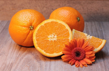 Ganze Orangen und geschnittene Orange auf Holzfläche